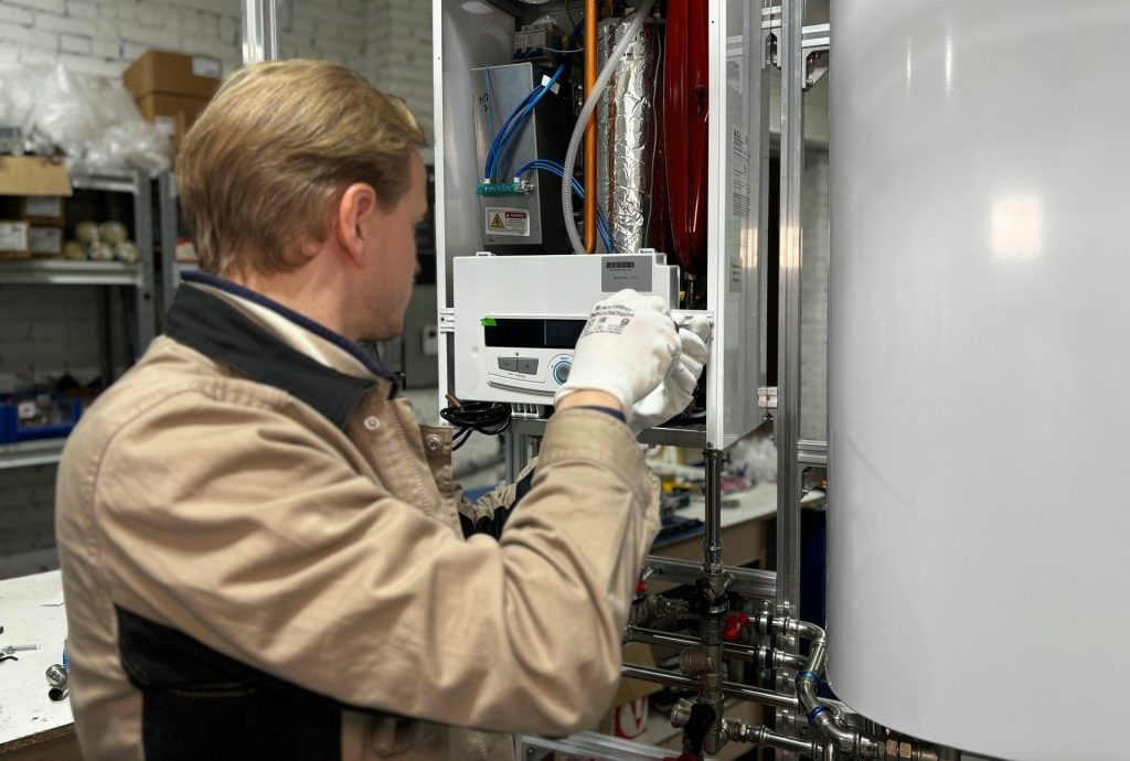 Technician installing or repairing a heating system in an indoor workshop setting.